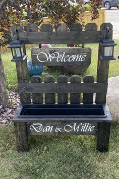 a wooden bench sitting in the grass with a welcome sign on it's back