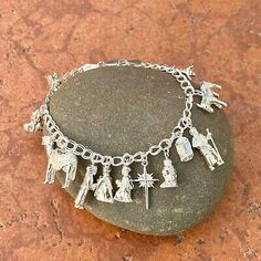 a silver bracelet with charms on top of a rock