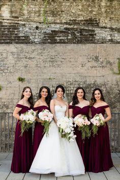 the bride and her bridesmaids pose for a photo in front of an old brick wall