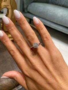 a woman's hand with white manicured nails and a ring on her finger