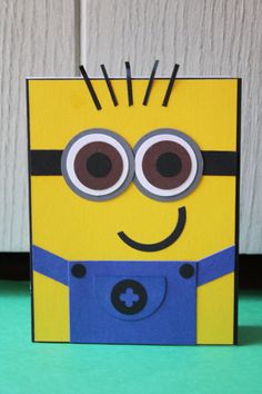 a paper cut out of a yellow and blue minion sitting on top of a table