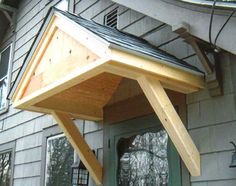 a wooden roof on the side of a house with an awning over it's door