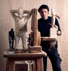 a man standing next to a wooden sculpture