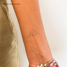 a woman's arm with a small sun tattoo on the left side of her wrist