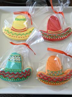 four decorated cookies in plastic bags on a tray