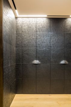 two urinals in the middle of a room with wood flooring and metal walls