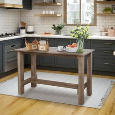 a wooden table in a kitchen next to a potted plant and bowl of fruit