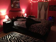 a bedroom decorated in pink and black with zebra print rugs on the floor, lights hanging from the ceiling