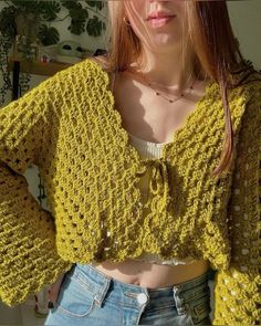 a woman wearing a yellow crochet sweater and jeans with her hands on her hips