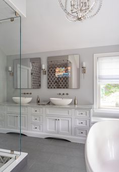 a large bathroom with two sinks and a bathtub in the corner, along with a chandelier