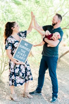 a man and woman holding up a sign that says we survived the first year in front of them