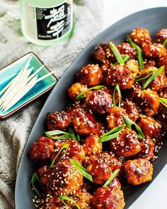 a plate full of chicken with sesame seeds on it next to a bottle of water