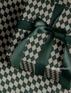 a green and white checkered gift box with a bow on it's side