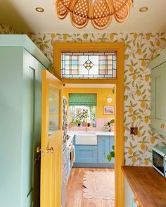 a kitchen with yellow and blue walls, wood flooring and a stained glass window