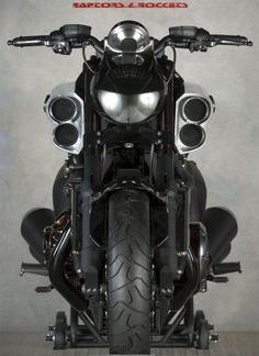 the front end of a black motorcycle with speakers on it's back tire rims