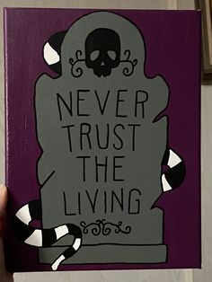 a hand holding up a purple and black sign with a skull on it that says never trust the living