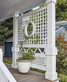 a white trellis on the side of a house next to a potted plant