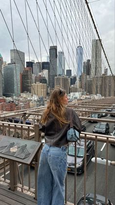 a woman standing on the side of a bridge