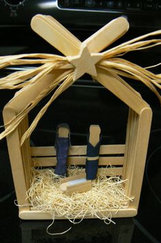 a nativity scene made out of wood sticks and straw with two blue candles in the manger