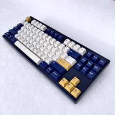 a computer keyboard sitting on top of a white table covered in blue and yellow keys