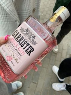 a person holding up a bottle of pink gin