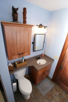 a bathroom with a toilet, sink and wooden cabinetry in the middle of it