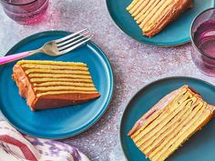 three plates with slices of cake on them next to two glasses and one pink fork