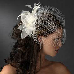 a woman wearing a veil with flowers on it's head and her hair in the wind