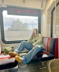 a man sitting on a train looking out the window while holding a cell phone to his ear