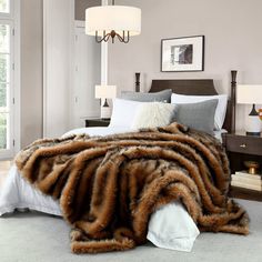 a bedroom with a bed covered in a brown and white fur blanket next to two lamps