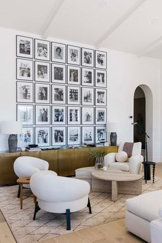 a living room filled with white furniture and pictures on the wall above it's coffee table