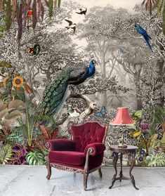 a peacock sitting on top of a red chair in front of a forest wall mural