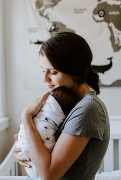 a woman holding a baby in her arms with a bottle hanging from the wall behind her