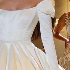 a woman in a wedding dress looking at herself in the mirror with her hand on her hip