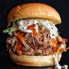 a pulled pork sandwich with coleslaw and slaw on a black table top