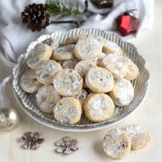 a bowl filled with cookies next to christmas decorations and pine cones on a white table