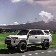 a white truck parked on the side of a road near a green grass covered field