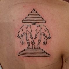 the back of a woman's shoulder with two elephants on it and a pyramid in the background