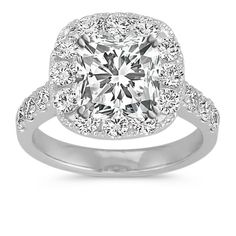 a cushion cut diamond ring with halos on the shoulders and sides, set in white gold