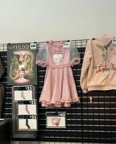 clothes are hanging up on the wall in front of posters and signs for children's clothing