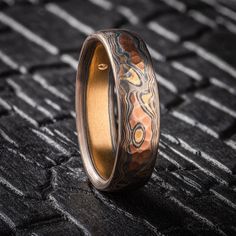 "* Price may vary depending on ring size, please inquire with us directly with your needed size for accurate pricing! This rustic feeling Mokume Gane band is shown in the Woodgrain pattern and the Firestorm metal combination, with a low dome profile, and an etched and oxidized and hammered finish. Firestorm features 14k red gold, 14k yellow gold, Palladium, and sterling silver.   Pattern: Woodgrain Palette: Firestorm  Finish: Etched & Oxidized Profile: Low Dome Width Shown: 6mm Size Shown: 11 Add Ons: Hammered Finish Price does NOT include stones or setting fees. We care about customer service and would like to hear from you! Please contact us to help create your treasured item, we take your concerns and requests to heart and will work together to create your unique designs SPECIAL PRICING Artisan Promise Ring, Artisan Rings With Patina And Adjustable Fit, Artisan Patina Rings For Anniversary, Ceremonial Oxidized Finish Ring, Mokume Gane Ring Wedding, Luxury Brutalist Men's Ring With Oxidized Finish, Mokume Gane Ring, Woodgrain Pattern, Mokume Gane