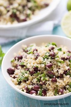 a white bowl filled with rice and beans next to limes on a blue table