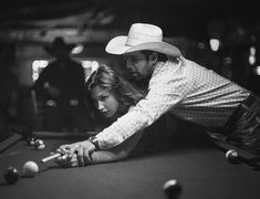 a man and woman leaning over a pool table with cues in their hands while playing billiard