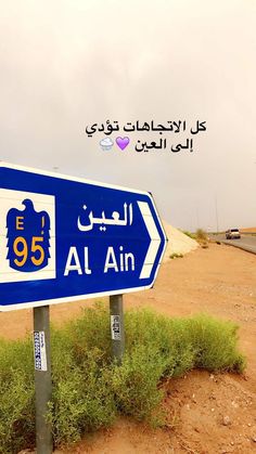 a blue and white street sign sitting on the side of a dirt road