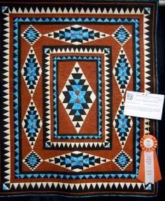 a quilt is displayed on display in a room with an orange ribbon around the corner