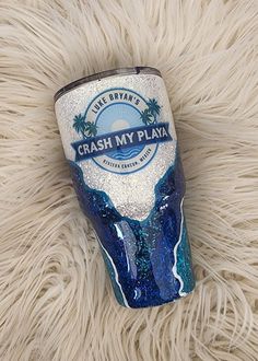 a blue and white cup with the words crash my playa on it sitting on a furry surface