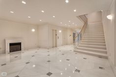 an empty white room with stairs leading up to the second floor and a fire place