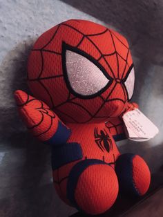 a spiderman stuffed animal sitting on top of a shelf next to a tag that says,