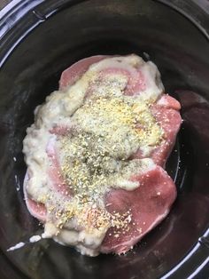 raw meat in a slow cooker with seasoning and salt sprinkled on top