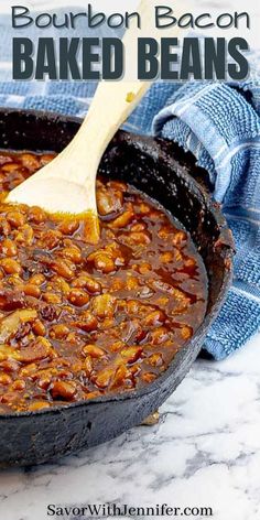 bacon baked beans in a cast iron skillet with a wooden spatula on top